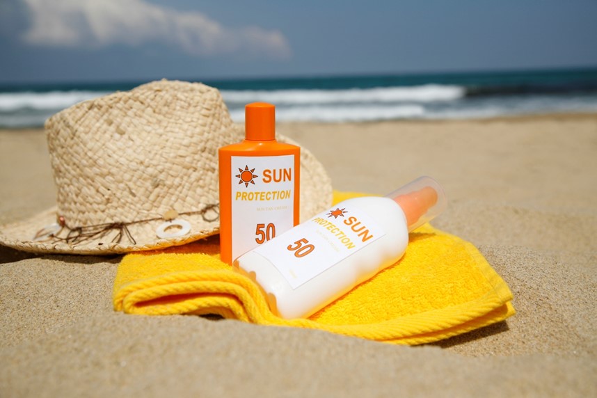 A sun protection lotion and a hat on a towel