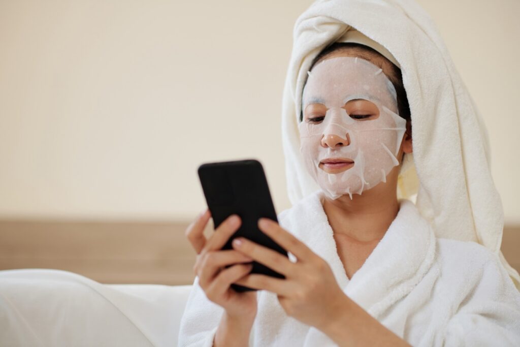 A person with a facial mask looking at their phone.